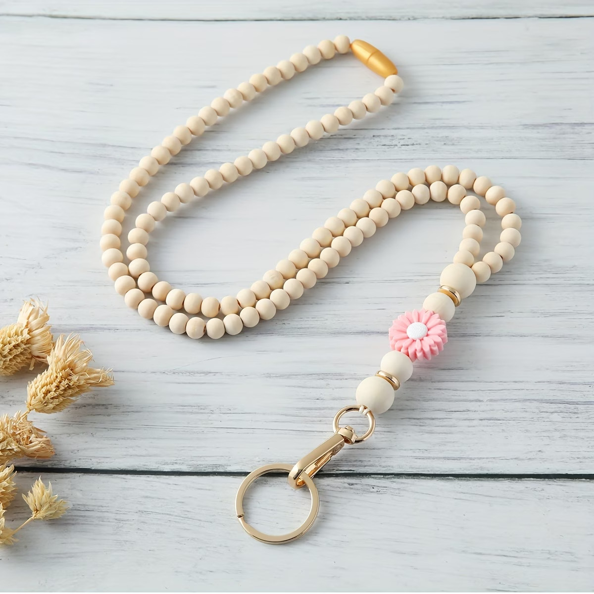 Handcrafted beaded lanyard featuring a soft blush pink silicone daisy focal, natural beechwood beads, and gold accents with a safety breakaway clasp by Woodland Beads & Co.