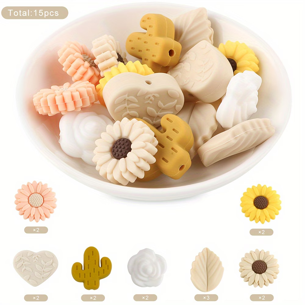 A 15-piece assortment of botanical DIY focal beads including mustard cacti, yellow and peach sunflowers, white roses, stone-colored leaves, and leaf-embossed hearts from Woodland Beads & Co.